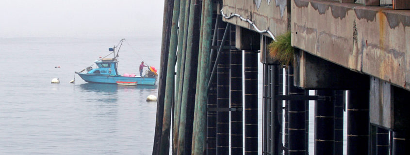 A fishing pier and small boat on a foggy ocean