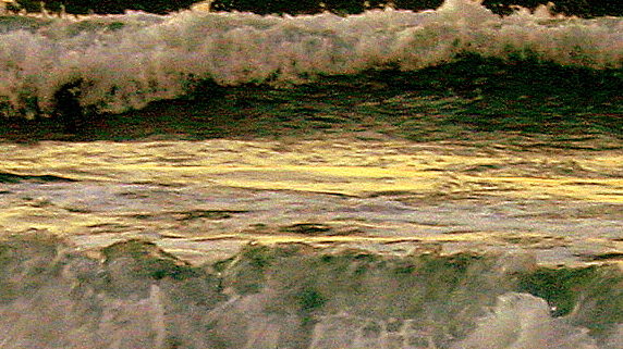 A dramatic line of waves rolls towards the camera