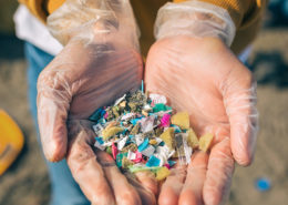 Gloved hands holding small colorful plastic pieces