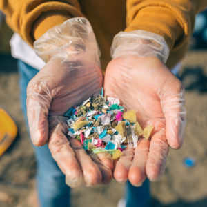 Gloved hands holding small colorful plastic pieces