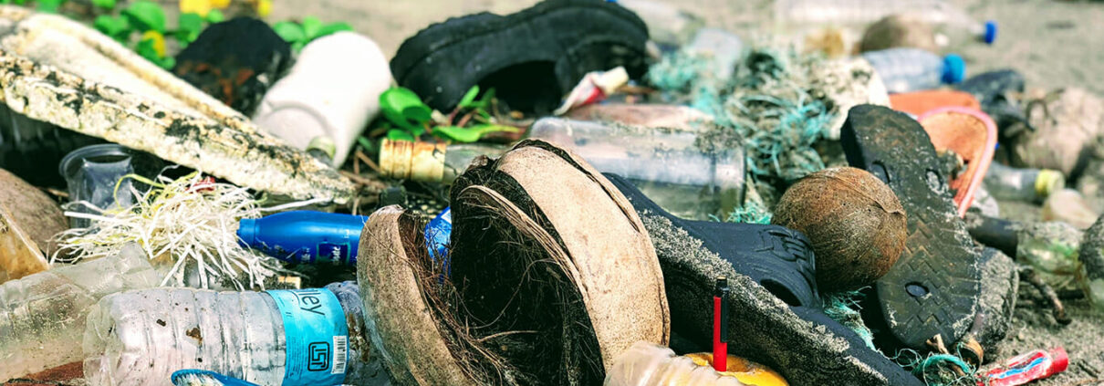 Plastic debris, including water bottles, shoes, and nets on a beach