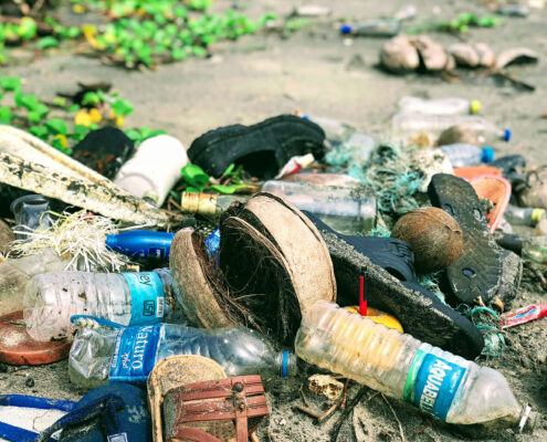 Plastic debris, including water bottles, shoes, and nets on a beach