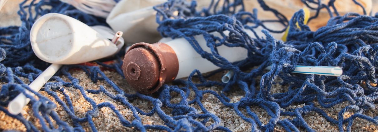 White and copper plastic bottles tangled in a net on the beach