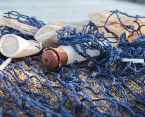 White and copper plastic bottles tangled in a net on the beach