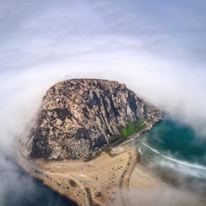 Aerial photo of Morro Rock and the parking lot for Morro Bay surrounded by fog