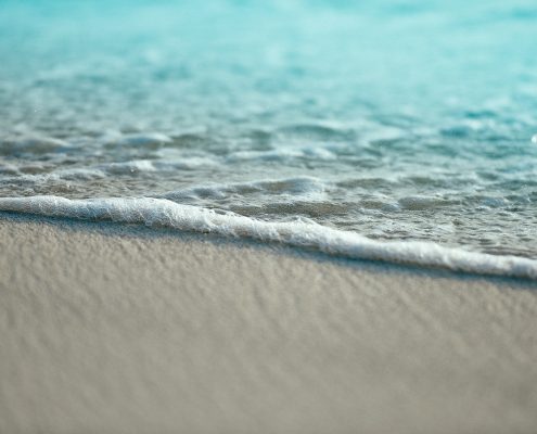 A close-up photo of sea foam on a white sand beach