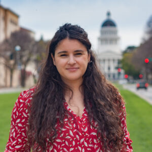 Photograph of a young brunette woman with the state capitol in the background