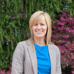 Photograph of a blonde woman in front of a green wall