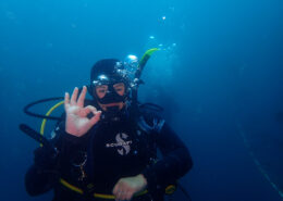 Photograph of a young woman making the OK gesture while SCUBA diving