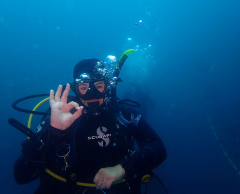Photograph of a young woman making the OK gesture while SCUBA diving