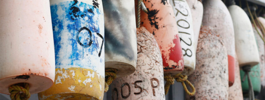 Fishing floats decorated with various markings hang from the eaves of a building