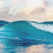 Close up of a cresting blue wave, with others visible in the background